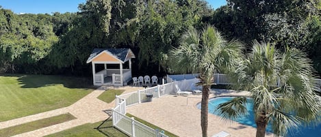 Ein Poolbereich mit Gazebo, Palmen und Liegestühlen.