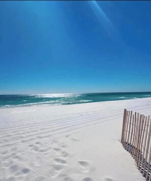 A beach with white sand and a wooden fence. - Beautifully furnished Front Beach Rd. condo five minute walk to beach. (Panama City Beach)