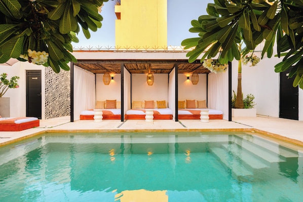 Una piscina al aire libre, camas de piscina gratis, sombrillas