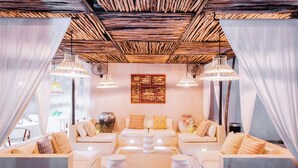 Una sala de estar moderna con techo de madera, sofás blancos y una mesa de centro.