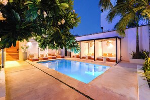 A swimming pool with lounge chairs and a glass-enclosed room with a bed. - Malish Hotel & Spa Luxury Edition (Playa del Carmen)