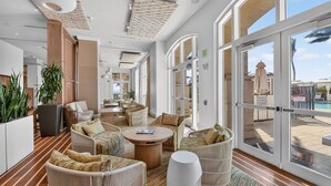 A spacious indoor area with wicker furniture, large windows, and a view of the pool outside.