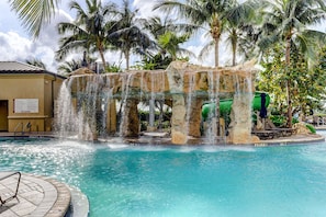 Une piscine agrémentée d’une cascade, de palmiers et d’un panneau indiquant qu’il est interdit de plonger.