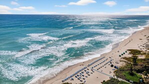 A beach with waves, a row of beach chairs, and umbrellas.