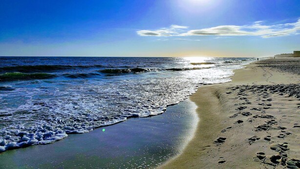 A beach with footprints in the sand, waves, and a clear sky. - Balcony to beach in minutes! Orange Beach tranquility all year at great rates! (Orange Beach)