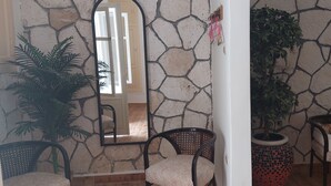 A room with a stone wall, a sofa, a chair, a potted plant, and a mirror. - Holiday home for special people (El-Agamy)