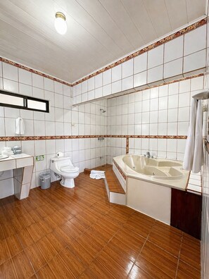 A bathroom with a toilet, sink, and bathtub, tiled walls, and wooden flooring.