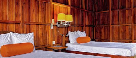 A wooden cabin room with two beds, a nightstand, and a lamp.