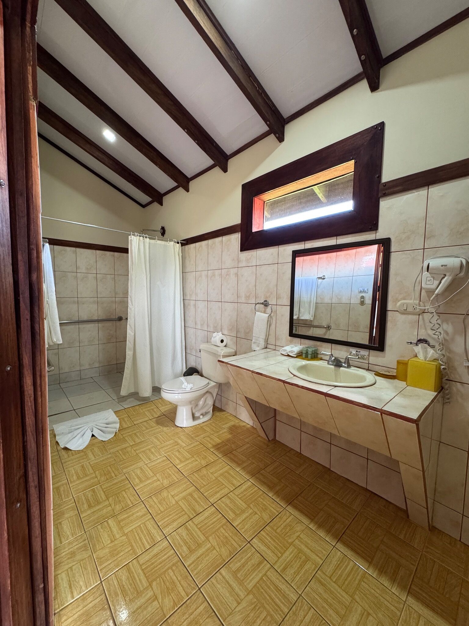 Un baño con ducha, inodoro, lavabo y espejo.