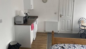 Una habitación pequeña con kitchenette, una cama, un radiador y una zona de comedor.