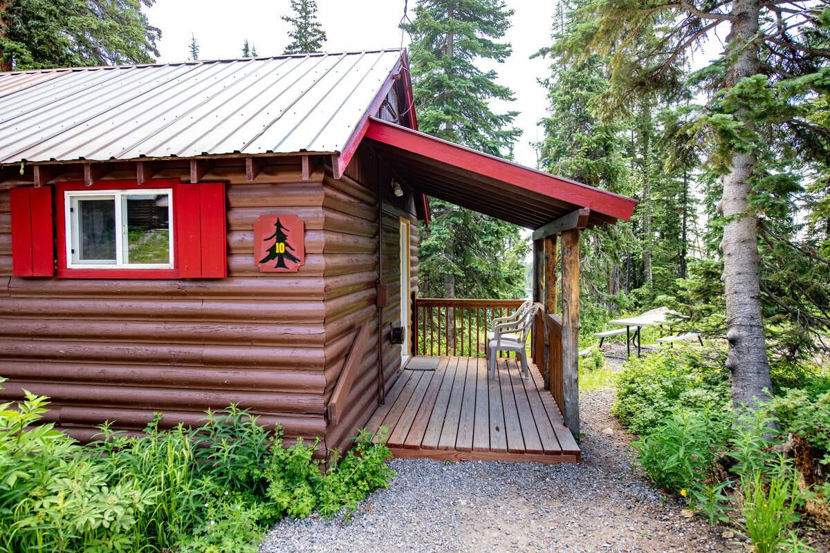 A rustic log cabin with a deck and a picnic table.