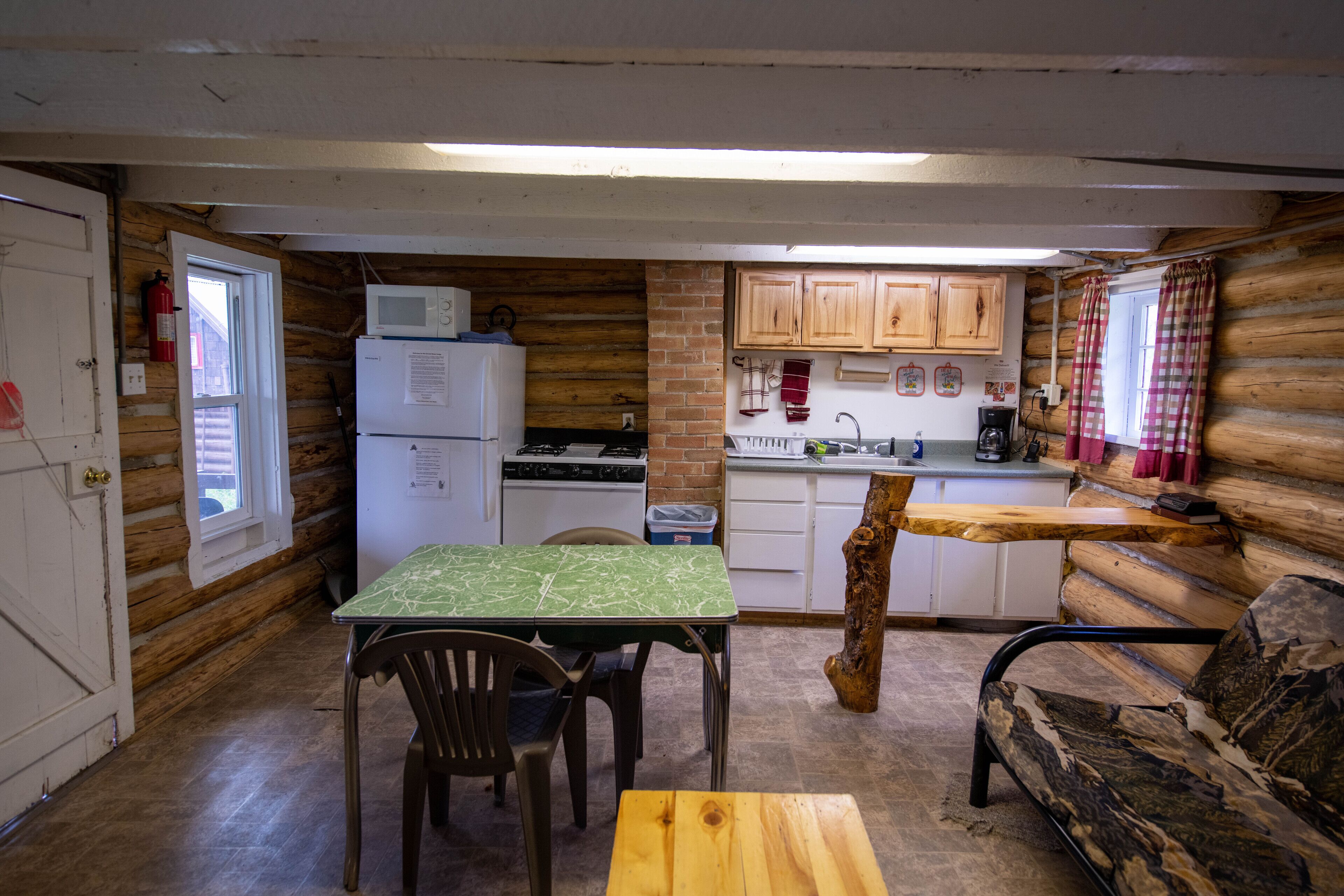 A compact log cabin interior with a kitchen, dining area, and a sofa.