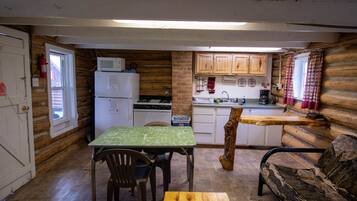 A compact log cabin interior with a kitchen, dining area, and a sofa.