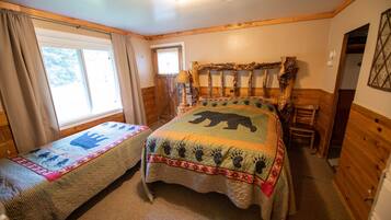 Un dormitorio con dos camas individuales, cabecero de madera, una ventana y una puerta.