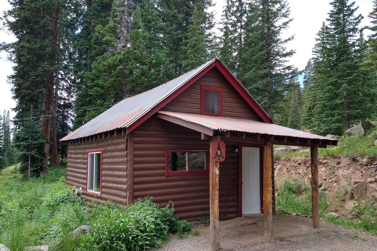 A small wooden cabin with a red roof, a door, and a window.