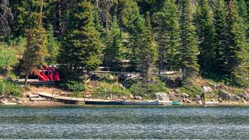 A dock with boats, a red structure, and a forested shoreline.