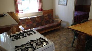 Una cocina acogedora con estufa a gas, una mesa de madera y un sofá estampado.