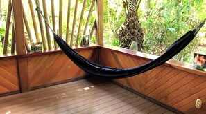 Una hamaca en una habitación de madera con vista a la vegetación.