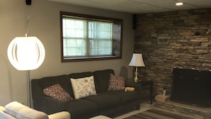 Ein Wohnzimmer mit Sofa, Lampe, Kamin und einer Steinwand.