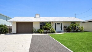 A single-story building with a garage, a front door, and a small porch with plants. - Paradise - Golf Cart Rental, Kayaks, Paddle Boat, Fishing & Swimming (Hernando Beach)