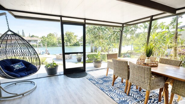 A spacious patio with a hanging chair, a dining table with wicker chairs, and potted plants. - Paradise - Golf Cart Rental, Kayaks, Paddle Boat, Fishing & Swimming (Hernando Beach)