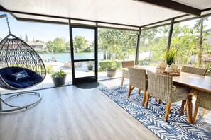 A spacious patio with a hanging chair, a dining table with wicker chairs, and potted plants. - Paradise - Golf Cart Rental, Kayaks, Paddle Boat, Fishing & Swimming (Hernando Beach)
