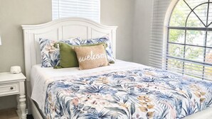 A bedroom with a white bed, floral bedding, a ceiling fan, and a window with blinds. - Paradise - Golf Cart Rental, Kayaks, Paddle Boat, Fishing & Swimming (Hernando Beach)