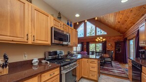 Une cuisine spacieuse avec des meubles en bois, un grand îlot central et un coin repas offrant une vue sur l’extérieur.