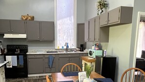 A compact kitchen with grey cabinets, a microwave, and a dining table set with chairs.