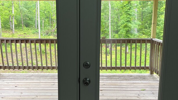 A wooden door with a glass panel, leading to an outdoor deck with a railing.