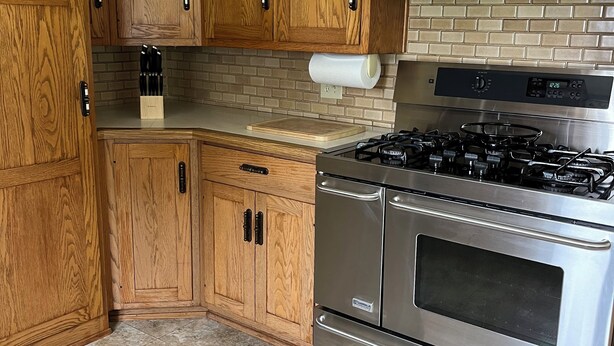 A kitchen with wooden cabinets, a gas stove, and a stainless steel oven.