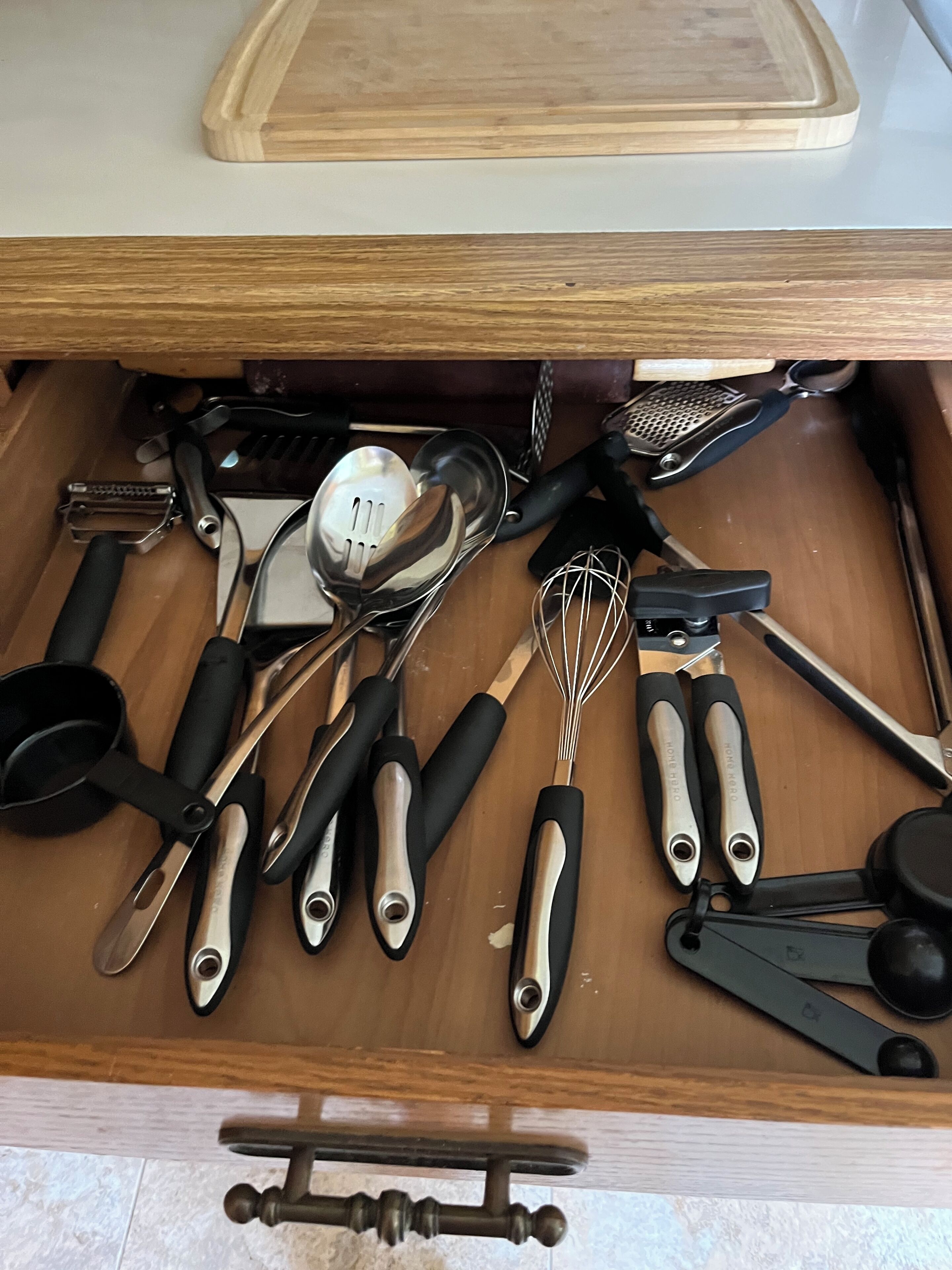Un tiroir de cuisine contenant divers ustensiles, notamment une râpe, des cuillères, un fouet et une spatule.