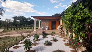Una casa con portico coperto, un giardino con diverse piante e vista sul paesaggio circostante.