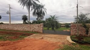 Un cancello chiuso con un muro in pietra, un cancello in metallo e un vialetto lastricato che conduce a un edificio.