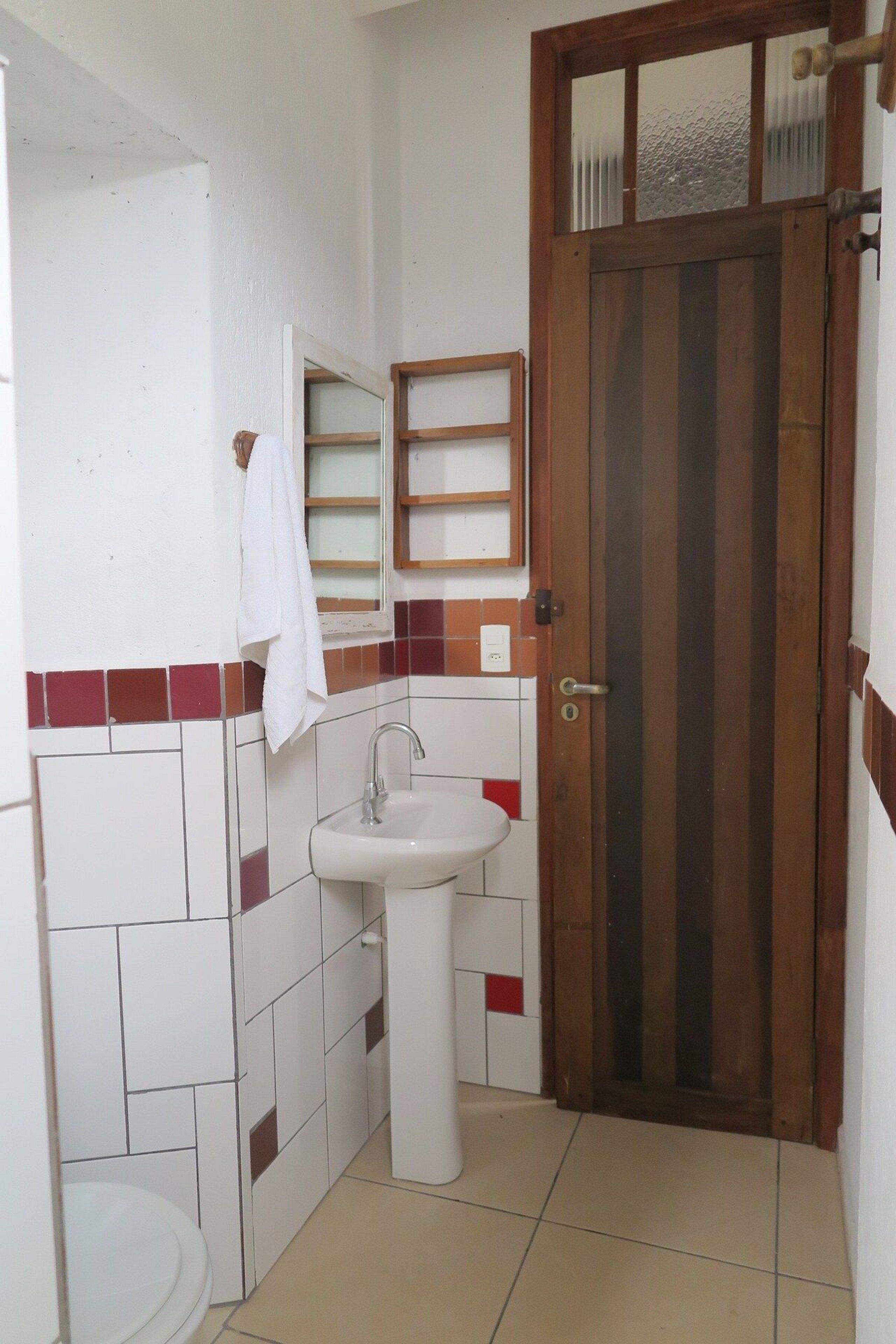 Un baño pequeño con lavamanos, espejo y retrete.
