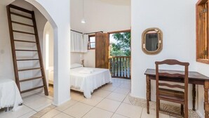 A bedroom with a bed, a wooden chair, a desk, a ladder, and a balcony with a view of greenery. - Pousart Floripa (Florianópolis)