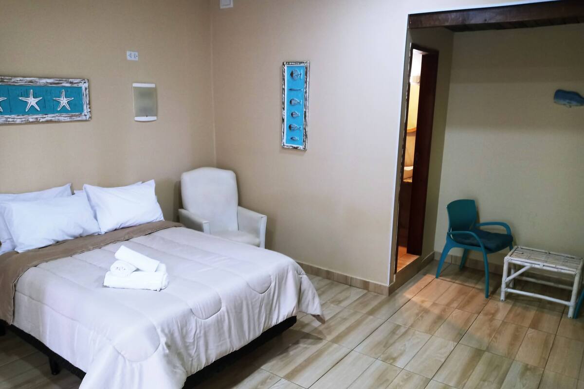 A hotel room with a bed, a chair, and a small table.