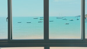 A view through a window of a coastal scene with several boats on the water. - Sabatico Beach House (Búzios)