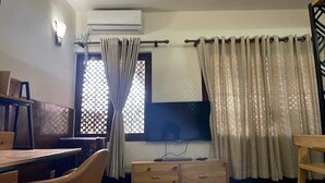 A room with a wooden desk, a television, a dresser, and a window with curtains. - MAKACH House, Studio Apartment !! (Kathmandu)