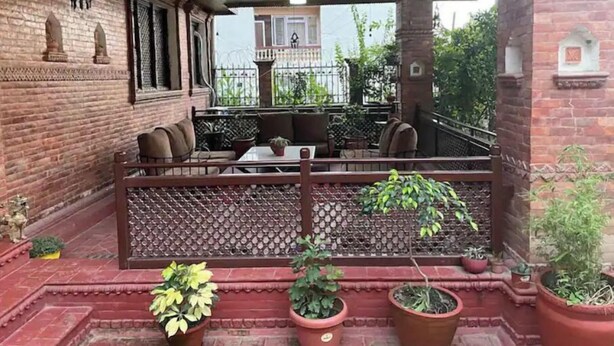 A covered outdoor seating area with brick walls, a wooden fence, and potted plants. - MAKACH House, Studio Apartment !! (Kathmandu)