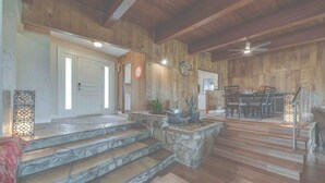 A spacious interior with a stone staircase leading to a wooden deck, a dining area with a table and chairs, and a ceiling fan. - Spacious bohemian canyon home with views (Reno)