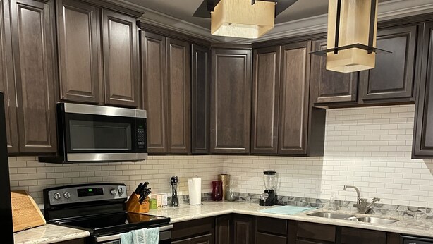 A modern kitchen with dark wood cabinets, stainless steel appliances, and a central island with a light blue towel.
