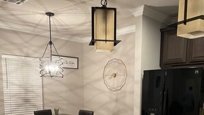 A modern kitchen with a central island, dark wood cabinetry, a black refrigerator, and pendant lighting.