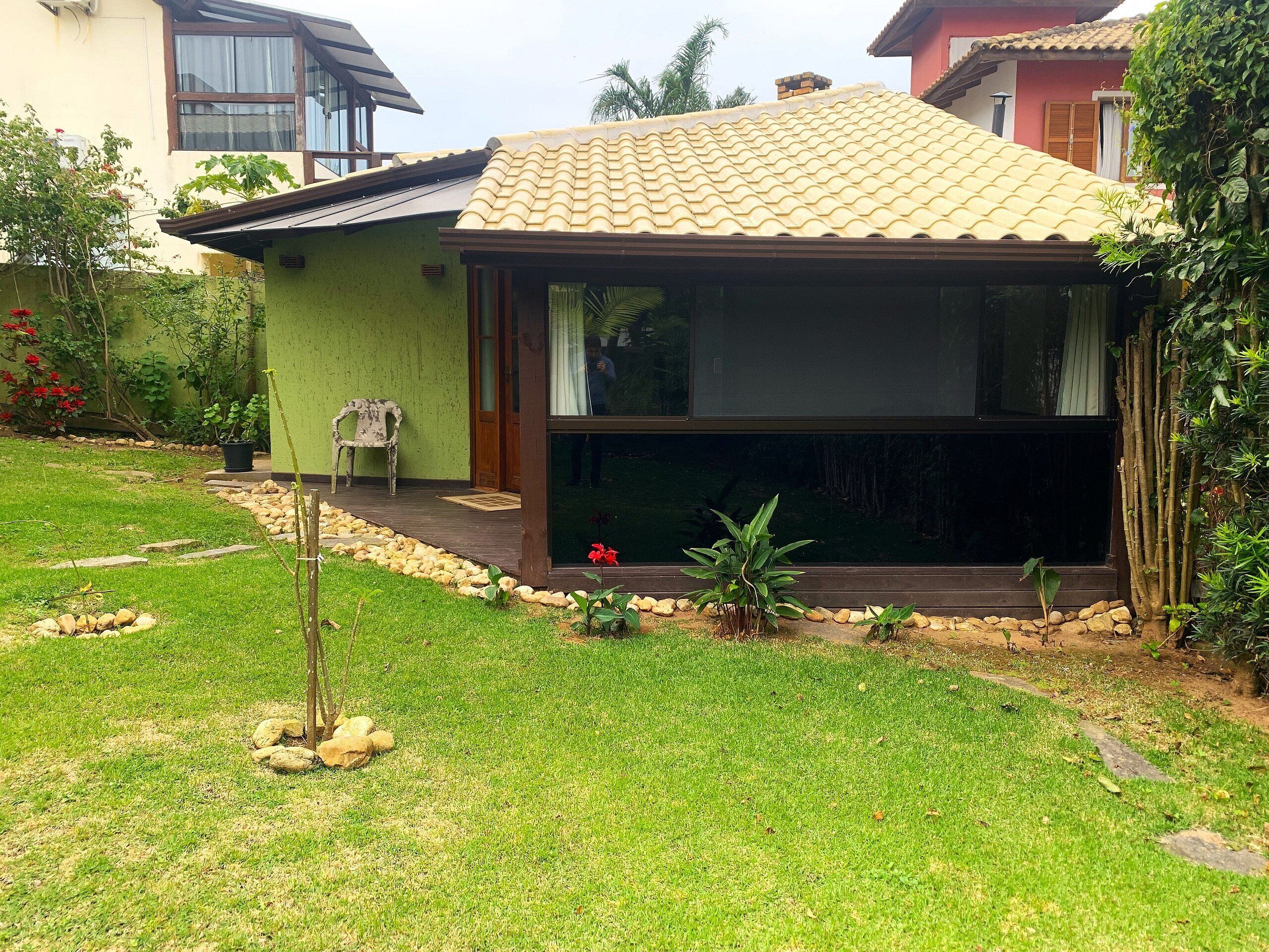 Uma casa com telhado de telhas, varanda coberta e jardim bem cuidado com pedras e plantas.