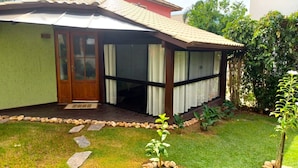 A house with a covered porch, a wooden door, and a small garden with stepping stones. - Loft's Jardim's - Campeche - Floripa (Florianópolis)