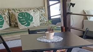A dining area with a wooden table, black chairs, and a floral cushion. - Loft's Jardim's - Campeche - Floripa (Florianópolis)