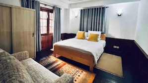 Ein Schlafzimmer mit Bett, Sofa, Kleiderschrank und einem Fenster mit Vorhängen.