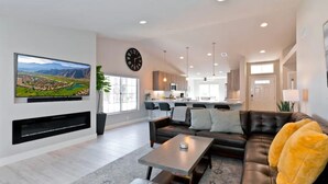 A modern living room with a leather sofa, a coffee table, and a flat-screen TV mounted on the wall. - Luxury Getaway - Casa Vaugeois (Palm Desert)