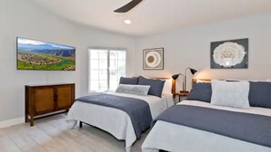 A bedroom with two beds, a wooden cabinet, and a large window. - Luxury Getaway - Casa Vaugeois (Palm Desert)