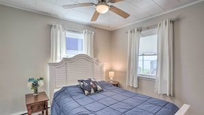 A bedroom with a bed, a nightstand, a ceiling fan, and a window with curtains. - Lakefront Cottage w/ Fishing & Private Yard! (Port Clinton)